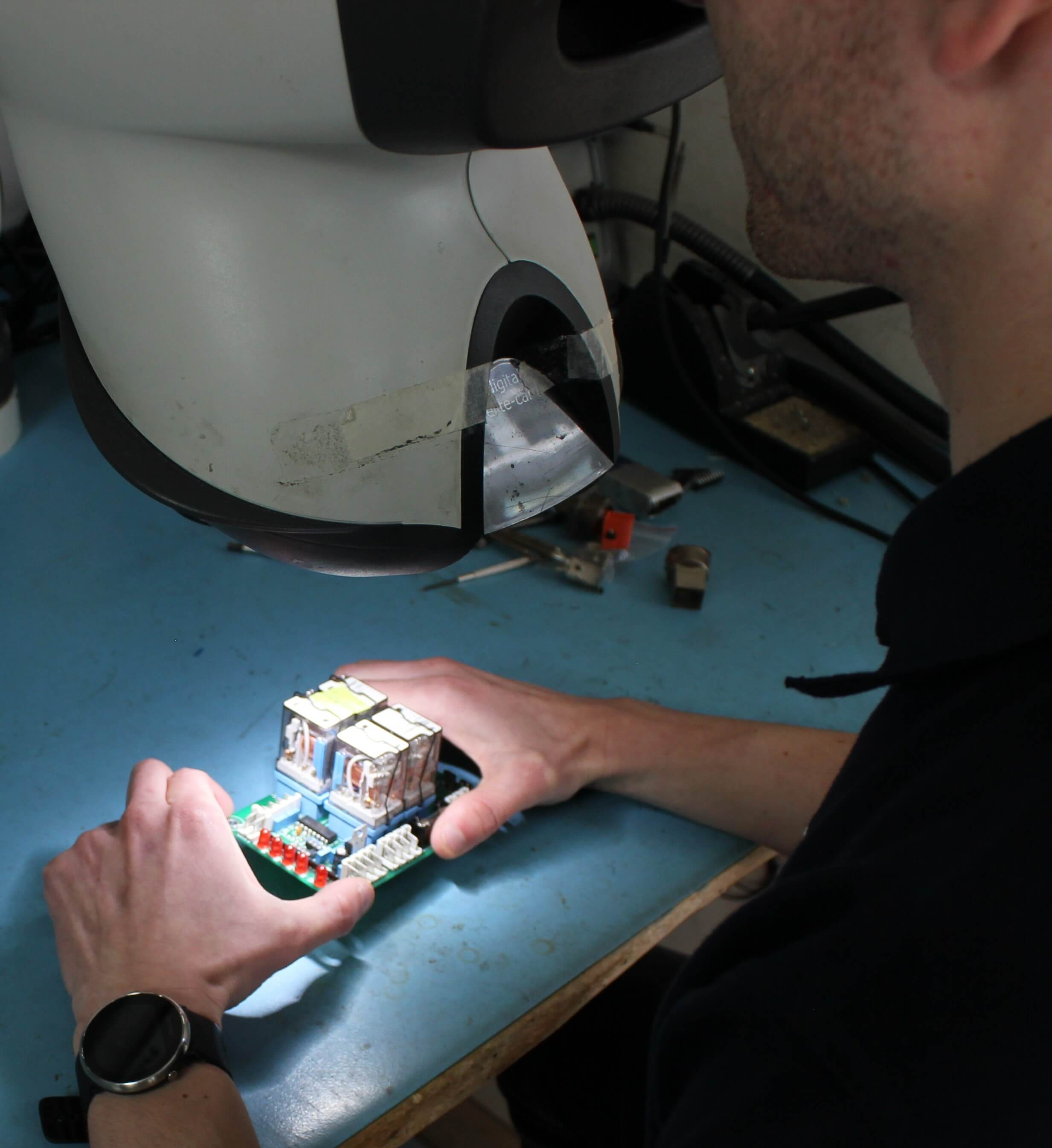 product engineer inspecting a populated circuit board under magnification