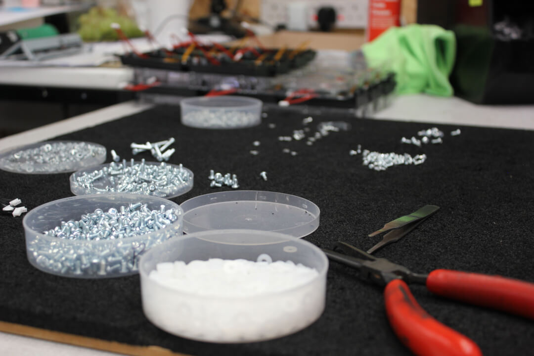 An image of various screws and spacers on a black foam mat
