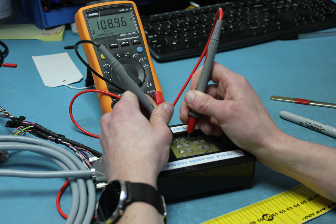An operator testing a cable assembly using a digital multimeter
