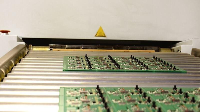 printed circuit boards moving along a conveyor away from baking oven