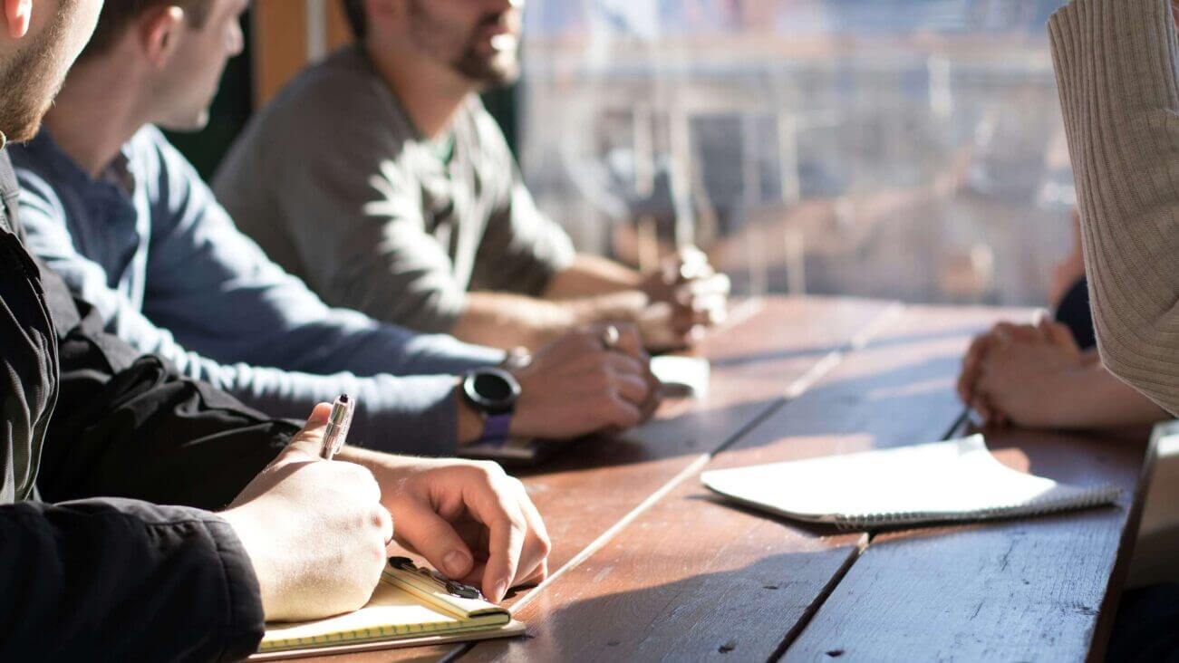 A team around a table discussing and taking notes