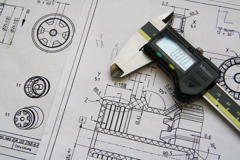 Image of mechanical schematics with a measuring tool laying on top.