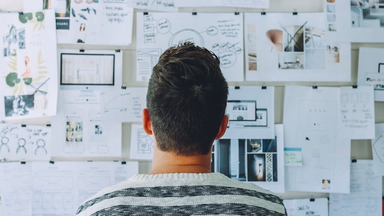 A man looking at notes pinned to a wall
