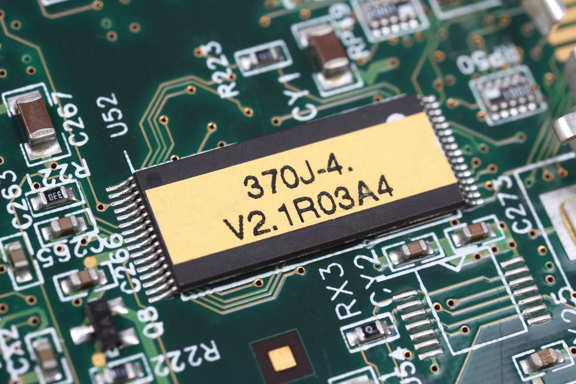 Closeup up of a green circuit board displaying a stamped serial number.